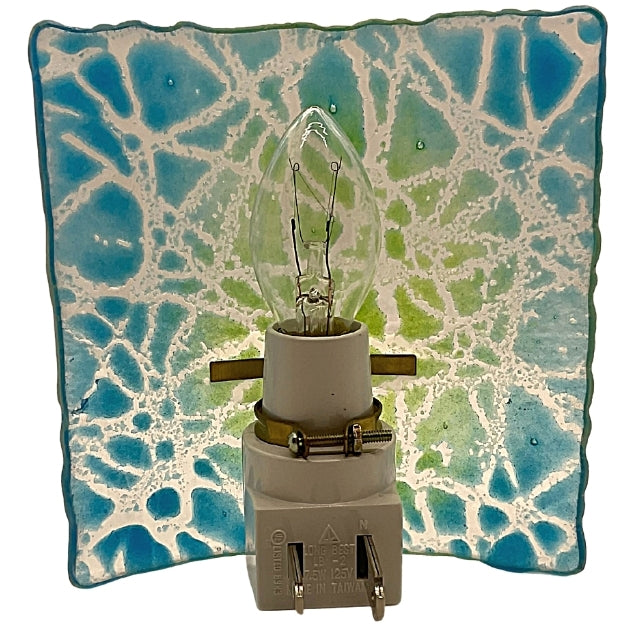 This shows the back of a fused glass night light. It shows a blue and green background with a crackling color of white.
